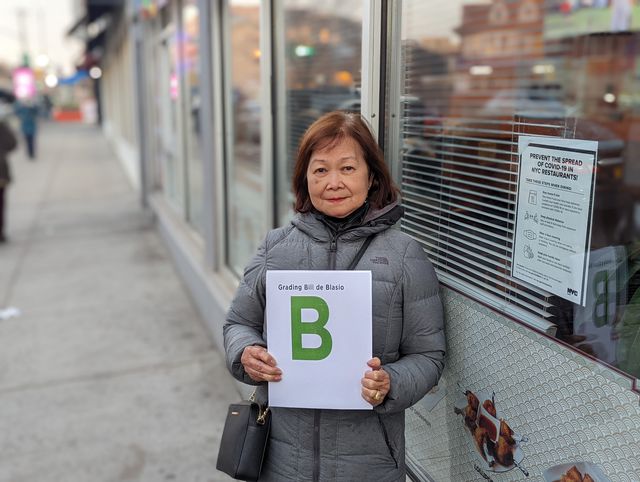 Minerva del Rosario of Queens holds up a sign grading Mayor Bill de Blasio's performance as mayor: a "B" grade.